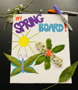 Colorful spring-themed craft project for children, featuring a poster labeled 'My Spring Board' with a sun, a butterfly, and a flower made from leaves, flowers, and markers, surrounded by crafting supplies on a table.