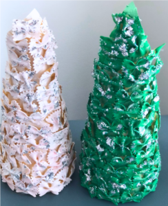 Two cone-shaped sculptures covered in bowtie pasta stand side by side. One is painted white, the other green, both adorned with silver glitter.