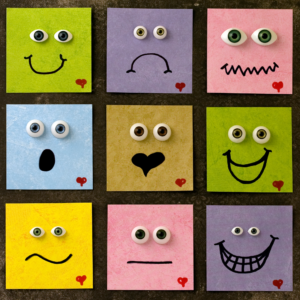 Nine colorful square faces with googly eyes display various emotions. Each has a unique expression, featuring smiles, frowns, and surprise, against a textured background.